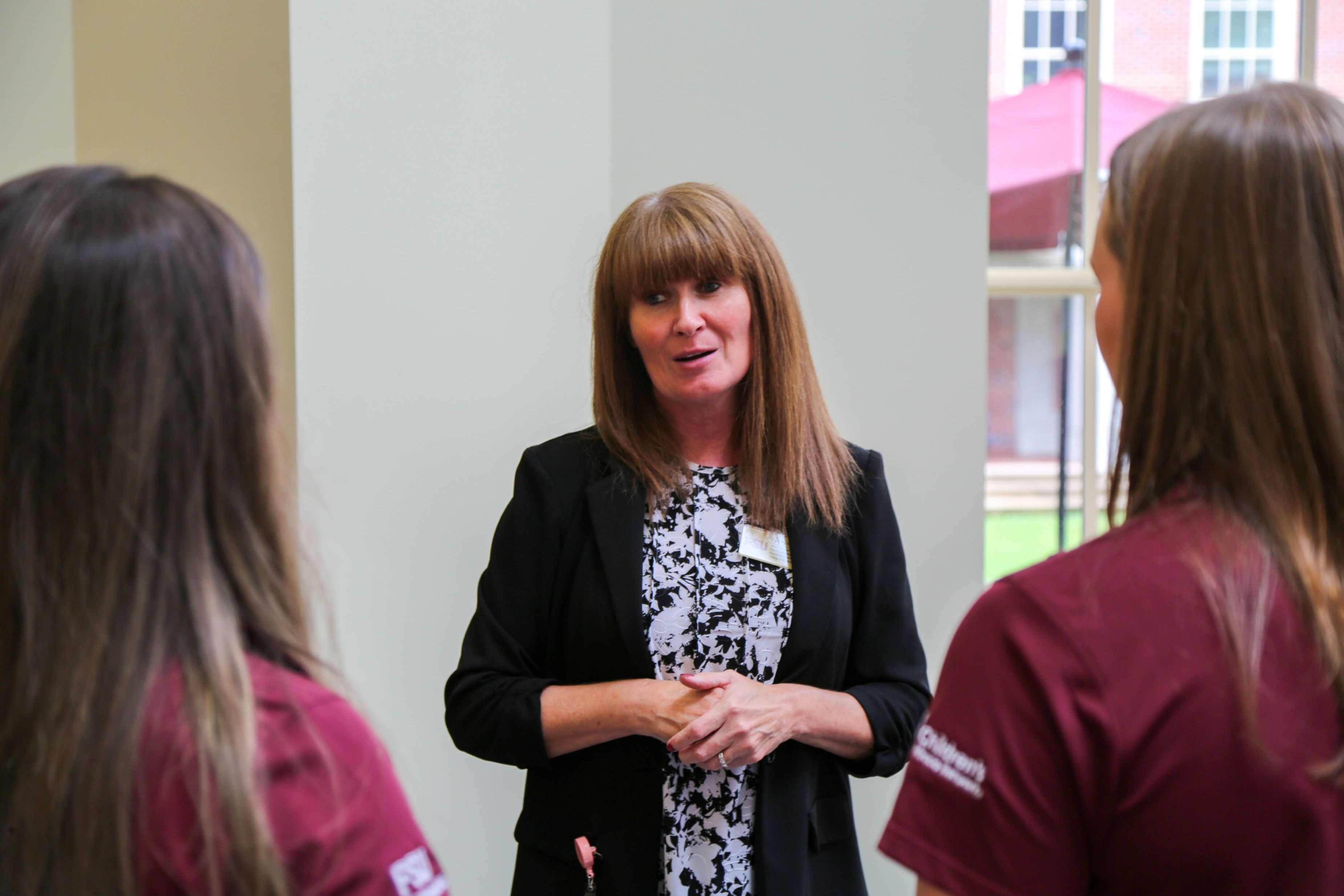 Pauline Hoffman talks with two Dance Marathon student leaders whose backs are to the camera.