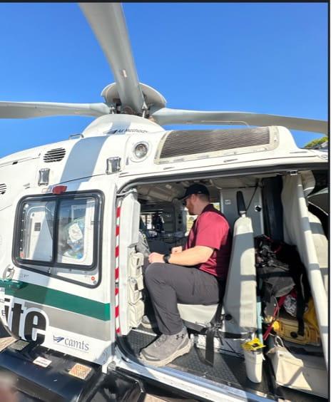 Fellow seated in a helicopter with the door open not in flight