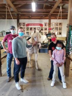 Third year medical students Tim Carter (left) and Ben Borgert (center left) volunteer with Hands and Hearts for Horses as part of their Community Medicine rotation.