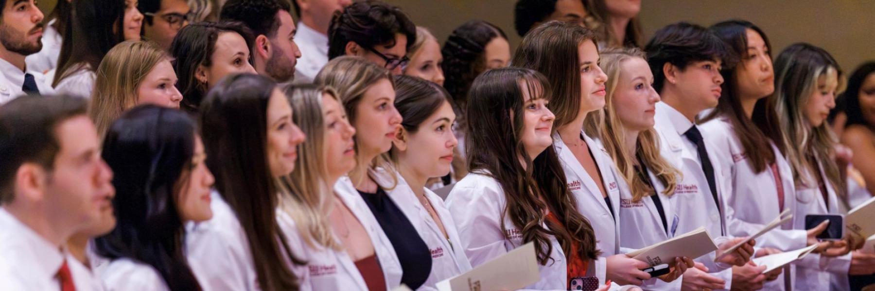 M.D. Class of 2030 students prepare to recite the medical student oath after receiving their white coats.
