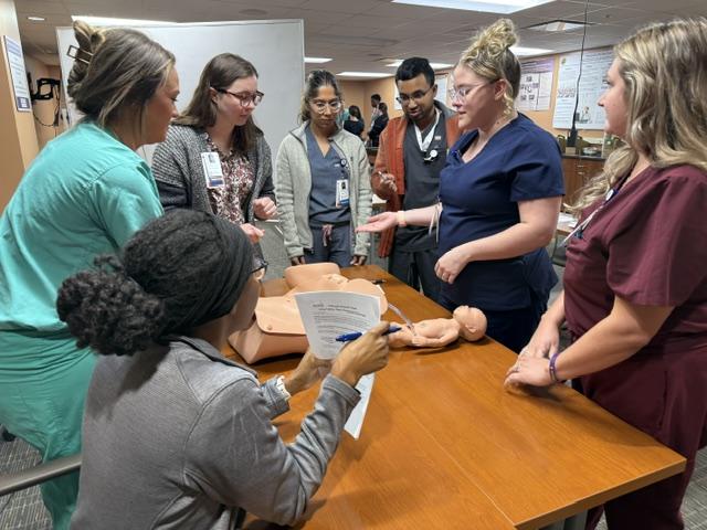 Residents gather around a table to look at a manikin