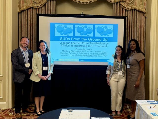 Faculty stand in front of a presentation on SUD treatment
