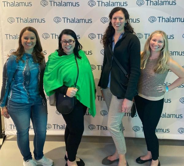 Faculty pose in front of a banner at the Thalamus event