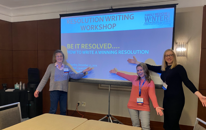 Faculty pose in front of a presentation for their resolution writing workshop