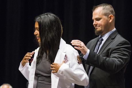 Michael Nair-Collins, Ph.D. coated his wife, Sangeeta Nair-Collins (M.D., '18), at the White Coat Ceremony in 2015